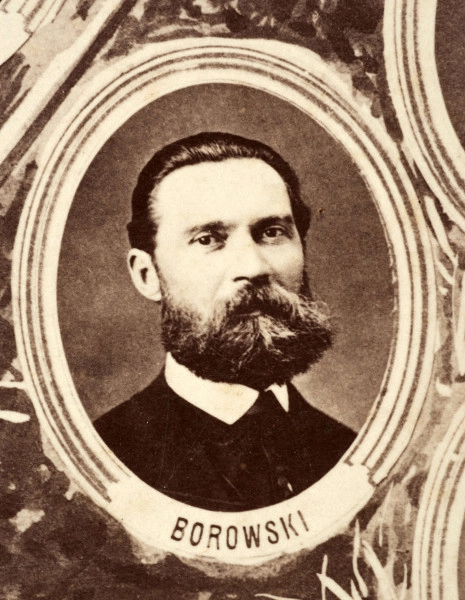 Fotografie w odcieniu sepii umieszczone na tle drzew i roślin, w centralnym miejscu postać kobiety ze sztandarem i aniołkami, wkomponowane widoki budowanej stacji, mostu kolejowego i lokomotywy. Największe zdjęcie w górnej, środkowej części bez podpisu, prawdopodobnie inż. głównej kolei nadwiślańskiej Tadeusz Chrzanowski lub jego następca Walery Titkow. Wśród podobizn pracownicy Biura Głównego Inżyniera: inż. Włodzimierz Stanisławski - pomocnik głównego inżyniera; inż. Feliks Kucharzewski -  pomocnik naczelnika biura; Feliks Kamocki - naczelnik kancelarii; Witold Lanci - naczelnik Wydz. Architektury; dr Wacław Lasocki- służba zdrowia; Władysław Radwan - sprawy zakupu gruntów; inż. Stanisław hr Scipio - projektant mostów kolejowych i jego współpracownicy: inż. Stefan Zieliński, inż. Maurycy Machalski, inż. Feliks Kucharzewski. Fotografia w passe - partout, za szkłem, oprawiona w drewnianą, profilowaną ramę.