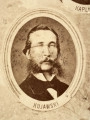 Fotografie w odcieniu sepii umieszczone na tle drzew i roślin, w centralnym miejscu postać kobiety ze sztandarem i aniołkami, wkomponowane widoki budowanej stacji, mostu kolejowego i lokomotywy. Największe zdjęcie w górnej, środkowej części bez podpisu, prawdopodobnie inż. głównej kolei nadwiślańskiej Tadeusz Chrzanowski lub jego następca Walery Titkow. Wśród podobizn pracownicy Biura Głównego Inżyniera: inż. Włodzimierz Stanisławski - pomocnik głównego inżyniera; inż. Feliks Kucharzewski -  pomocnik naczelnika biura; Feliks Kamocki - naczelnik kancelarii; Witold Lanci - naczelnik Wydz. Architektury; dr Wacław Lasocki- służba zdrowia; Władysław Radwan - sprawy zakupu gruntów; inż. Stanisław hr Scipio - projektant mostów kolejowych i jego współpracownicy: inż. Stefan Zieliński, inż. Maurycy Machalski, inż. Feliks Kucharzewski. Fotografia w passe - partout, za szkłem, oprawiona w drewnianą, profilowaną ramę.
