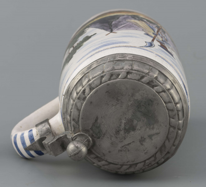 S/CS/64/ML - Korpus cylindryczny z uchem w kształcie litery „C”, pokrywka cynowa, płaska z profilowanym brzegiem i kulistą sterczyną  na zawiasie umocowanym do ucha; profilowana cynowa obręcz otacza dolną krawędź. Pokryty białym szkliwem z wielobarwną dekoracją malowaną skomponowaną przeciwlegle do ucha. Przedstawia ona w uproszczony sposób scenę w obozie  wojskowym: dwaj uzbrojeni kosynierzy stoją na wprost siebie, za nimi widoczny namiot a wokół zielone zarośla i drzewa. Niebo zaznaczone błękitnymi plamami, w tym samym kolorze malowane paski obiegają krawędzie naczynia i zdobią ucho. Tematyka przedstawienia ma wyraźnie patriotyczny charakter nawiązując do powstania kościuszkowskiego.

