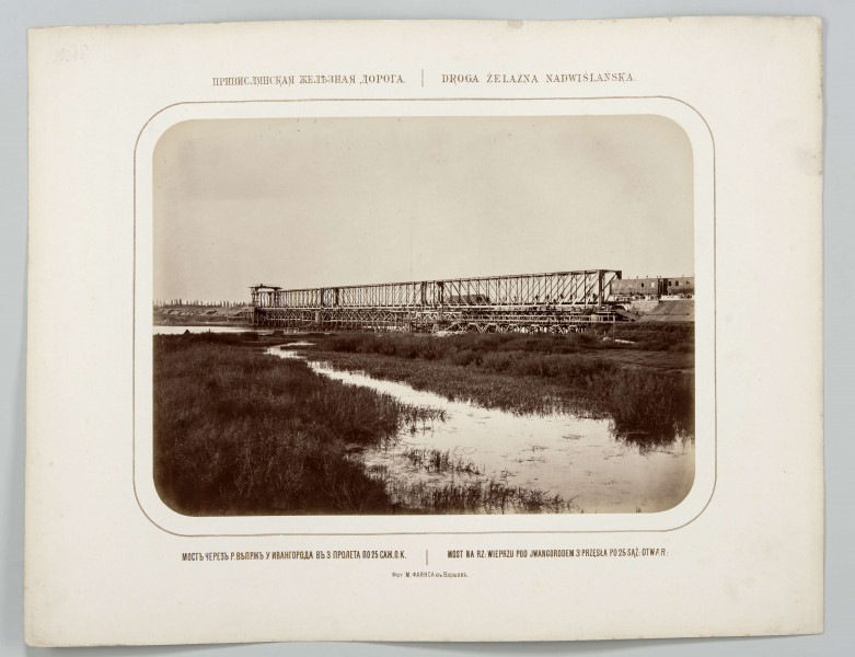 Na pierwszym planie rozlewisko rzeki porośnięte trawą. Dalej most żelazny kratowy długości 165 m, trzy przęsła po 53 m. Na prawym brzegu na nasypie wagony i kilku mężczyzn. Na przeciwległym brzegu widoczne rusztowanie. Fotografia o zaokrąglonych rogach, obrysowana dookoła cienką ramką, naklejona na tekturę. Powyżej i pod fotografią napisy po rosyjsku - z lewej i po polsku - z prawej strony. W dolnej części informacja o autorze zdjęcia po rosyjsku.
