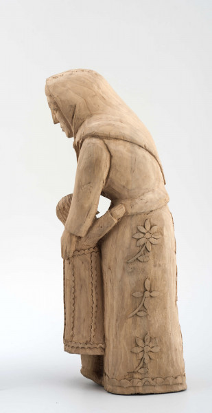 Rzeźba w drewnie lipowym, niepolichromowana, przedstawiająca postać kobiety nachylonej nad dzieckiem, stojącym przy kolanach. Kobieta w chustce na głowie zawiązanej pod brodą, o twarzy trójkątnej, dużych oczach, wąskich ustach. Ubrana w bluzkę z długimi rękawami i serdak z zaznaczoną baskinką , w długiej spódnicy pokrytej stylizowanymi wielopłatkowymi kwiatami na gałązce. U dołu biegnie pasek w formie falistej linii. Kobieta obejmuje rękami dziecko, zwrócone do niej twarzą. Dziecko z włosami sięgającymi do szyi, zaznaczonymi rowkowanymi nacięciami – uczesane z przedziałkiem  pośrodku. W długiej sukience, ozdobionej falistymi liniami poziomymi u dołu i góry, pionowymi pośrodku. 