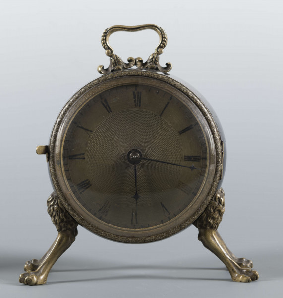 S/Mt/430/ML - Obudowa z brązu w formie bębna leżącego na czterech zwierzęcych łapach, pokrytego czarnym lakierem, z pionowym uchwytem w formie rozciągniętej profilowanej, wolutki. Tarcza zegarowa z mosiądzu, okrągła, moletowana mz malowanymi czarnymi cyframi rzymskimi godzin i oznaczeniem minut; dwie proste wskazówki; osłonieta zamykaną szybką o wypukłym profilu. Zamknięcie z tyłu w postaci okrągłych drzwiczek na zawiasie, z wmontowanym jednym dzwonkiem. Mechanizm mosiężny, o naciągu sprężynowym, z biciem godzin i kwadransów.
Na płycie wewnętrznej mechanizmu grawerowana sygnatura kursywą:
- Jacobus Staigier Lublin
