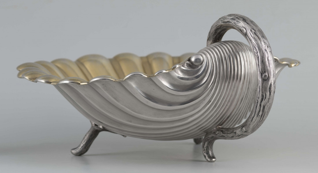 S/Mt/504/ML - Patera z uchwytem, w formie muszli przegrzebka ustawionej poziomo na  dwóch nóżkach - trzecią nóżkę tworzy zakończenie pionowo umocowanego esowatego ucha. 
Na odwrocie sygnatura segmentowa:
- znak miejski Petersburga
- znak imienny złotnika  