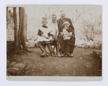 Fotografia przedstawia Michała Żyborskiego z Jerzym Polem (swym zięciem) i jego dziećmi: Jadwigą i Zbigniewem (wnukami Michała). Po lewej siedzi Jerzy trzymający na prawym kolanie kilkuletnią Jadwigę. Z prawej Michał Żyborski, a między jego kolanami stoi mały Zbysio. Tło stanowi fragment ogrodzenia z siatki oraz drzewa i krzewy bez liści. 