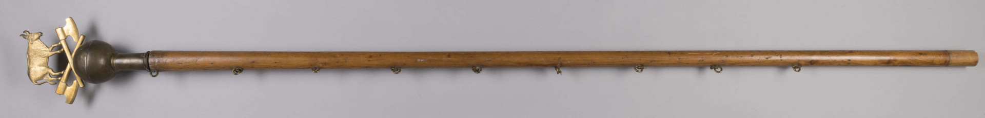 ML/H/959 - Sztandar Zgromadzenia Majstrów Rzeźniczych m. Lublina. Na awersie na amarantowym wzorzystym tle postać św. Jana Nepomucena w szatach pontyfikalnych, z krzyżem i gałązką palmową w dłoni oraz z Dzieciątkiem Jezus. W tle krajobraz z zabudowaniami i wieżami kościołów. Wokół haftowany ornament roślinny. Twarz i dłonie postaci malowane olejną farbą. Na rewersie haftowane złotą nicią napisy z nazwiskami starszego, podstarszego, podskarbiego cechu oraz ojca gospodniego. Nad nimi owieczka w pozycji leżącej ułożona na podstawie w formie krzyża. Wokół ornament kwiatowo-roślinny ze stylizowanymi liliami. Między ornamentami obu stron sztandaru wszyte ozdobne cekiny. Wokół sztandaru w formacie zbliżonym do kwadratu ozdobne frędzle. Po jednej stronie doszyte kółka do podtrzymywania sztandaru. Drzewiec zwieńczony blaszaną kulą ze skrzyżowanymi toporami oraz wołem pośrodku.