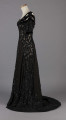 S/T/243/ML - Suknia wizytowa, czarna, uszyta z atłasu jedwabnego, jedwabnego tiulu i aksamitu, haftowana cekinami. Krótki rękaw z jedwabnego czarnego aksamitu, dekolt prostokatny, dość głęboki, wykończony wstawką haftowaną i aksamitem. Kolory są kontrastowe. Spodnia warstwa sukni, z białej tafty i muślinu, widoczna w partiach sukni szytych z czarnego tiulu, dodaje całości elegancji. Brzegi dekoracyjnej wici z tafty zaakcentowane naszytymi cekinami. Suknia do ziemi z tyłu krótki tren. Brak halki. 