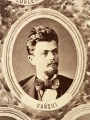Fotografie w odcieniu sepii umieszczone na tle drzew i roślin, w centralnym miejscu postać kobiety ze sztandarem i aniołkami, wkomponowane widoki budowanej stacji, mostu kolejowego i lokomotywy. Największe zdjęcie w górnej, środkowej części bez podpisu, prawdopodobnie inż. głównej kolei nadwiślańskiej Tadeusz Chrzanowski lub jego następca Walery Titkow. Wśród podobizn pracownicy Biura Głównego Inżyniera: inż. Włodzimierz Stanisławski - pomocnik głównego inżyniera; inż. Feliks Kucharzewski -  pomocnik naczelnika biura; Feliks Kamocki - naczelnik kancelarii; Witold Lanci - naczelnik Wydz. Architektury; dr Wacław Lasocki- służba zdrowia; Władysław Radwan - sprawy zakupu gruntów; inż. Stanisław hr Scipio - projektant mostów kolejowych i jego współpracownicy: inż. Stefan Zieliński, inż. Maurycy Machalski, inż. Feliks Kucharzewski. Fotografia w passe - partout, za szkłem, oprawiona w drewnianą, profilowaną ramę.