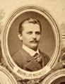 Fotografie w odcieniu sepii umieszczone na tle drzew i roślin, w centralnym miejscu postać kobiety ze sztandarem i aniołkami, wkomponowane widoki budowanej stacji, mostu kolejowego i lokomotywy. Największe zdjęcie w górnej, środkowej części bez podpisu, prawdopodobnie inż. głównej kolei nadwiślańskiej Tadeusz Chrzanowski lub jego następca Walery Titkow. Wśród podobizn pracownicy Biura Głównego Inżyniera: inż. Włodzimierz Stanisławski - pomocnik głównego inżyniera; inż. Feliks Kucharzewski -  pomocnik naczelnika biura; Feliks Kamocki - naczelnik kancelarii; Witold Lanci - naczelnik Wydz. Architektury; dr Wacław Lasocki- służba zdrowia; Władysław Radwan - sprawy zakupu gruntów; inż. Stanisław hr Scipio - projektant mostów kolejowych i jego współpracownicy: inż. Stefan Zieliński, inż. Maurycy Machalski, inż. Feliks Kucharzewski. Fotografia w passe - partout, za szkłem, oprawiona w drewnianą, profilowaną ramę.