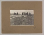 ML/H/F/26/6 - Fotografia przedstawia mężczyzn stojących w dwóch grupach. Po lewej cztery postaci, po prawej dziesięć. Kilku z nich trzyma kartkę papieru. W ziemi widać doły. Fotografia naklejona na brązową tekturę z wytłoczoną ramką. W prawym dolnym rogu pieczęć zakładu fotograficznego S. Zawadzkiego z Lublina.