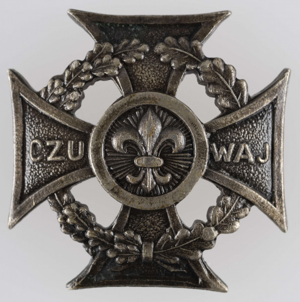 ML/MART/373 - Krzyż harcerski 4-ramienny wykonany z metalu, na środku lilijka harcerska, krzyż otaczają liście wawrzynu; napis na bocznych ramionach 