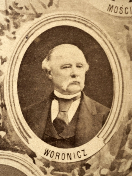 Fotografie w odcieniu sepii umieszczone na tle drzew i roślin, w centralnym miejscu postać kobiety ze sztandarem i aniołkami, wkomponowane widoki budowanej stacji, mostu kolejowego i lokomotywy. Największe zdjęcie w górnej, środkowej części bez podpisu, prawdopodobnie inż. głównej kolei nadwiślańskiej Tadeusz Chrzanowski lub jego następca Walery Titkow. Wśród podobizn pracownicy Biura Głównego Inżyniera: inż. Włodzimierz Stanisławski - pomocnik głównego inżyniera; inż. Feliks Kucharzewski -  pomocnik naczelnika biura; Feliks Kamocki - naczelnik kancelarii; Witold Lanci - naczelnik Wydz. Architektury; dr Wacław Lasocki- służba zdrowia; Władysław Radwan - sprawy zakupu gruntów; inż. Stanisław hr Scipio - projektant mostów kolejowych i jego współpracownicy: inż. Stefan Zieliński, inż. Maurycy Machalski, inż. Feliks Kucharzewski. Fotografia w passe - partout, za szkłem, oprawiona w drewnianą, profilowaną ramę.