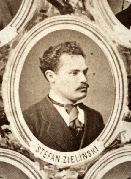Fotografie w odcieniu sepii umieszczone na tle drzew i roślin, w centralnym miejscu postać kobiety ze sztandarem i aniołkami, wkomponowane widoki budowanej stacji, mostu kolejowego i lokomotywy. Największe zdjęcie w górnej, środkowej części bez podpisu, prawdopodobnie inż. głównej kolei nadwiślańskiej Tadeusz Chrzanowski lub jego następca Walery Titkow. Wśród podobizn pracownicy Biura Głównego Inżyniera: inż. Włodzimierz Stanisławski - pomocnik głównego inżyniera; inż. Feliks Kucharzewski -  pomocnik naczelnika biura; Feliks Kamocki - naczelnik kancelarii; Witold Lanci - naczelnik Wydz. Architektury; dr Wacław Lasocki- służba zdrowia; Władysław Radwan - sprawy zakupu gruntów; inż. Stanisław hr Scipio - projektant mostów kolejowych i jego współpracownicy: inż. Stefan Zieliński, inż. Maurycy Machalski, inż. Feliks Kucharzewski. Fotografia w passe - partout, za szkłem, oprawiona w drewnianą, profilowaną ramę.
