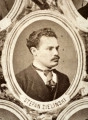 Fotografie w odcieniu sepii umieszczone na tle drzew i roślin, w centralnym miejscu postać kobiety ze sztandarem i aniołkami, wkomponowane widoki budowanej stacji, mostu kolejowego i lokomotywy. Największe zdjęcie w górnej, środkowej części bez podpisu, prawdopodobnie inż. głównej kolei nadwiślańskiej Tadeusz Chrzanowski lub jego następca Walery Titkow. Wśród podobizn pracownicy Biura Głównego Inżyniera: inż. Włodzimierz Stanisławski - pomocnik głównego inżyniera; inż. Feliks Kucharzewski -  pomocnik naczelnika biura; Feliks Kamocki - naczelnik kancelarii; Witold Lanci - naczelnik Wydz. Architektury; dr Wacław Lasocki- służba zdrowia; Władysław Radwan - sprawy zakupu gruntów; inż. Stanisław hr Scipio - projektant mostów kolejowych i jego współpracownicy: inż. Stefan Zieliński, inż. Maurycy Machalski, inż. Feliks Kucharzewski. Fotografia w passe - partout, za szkłem, oprawiona w drewnianą, profilowaną ramę.