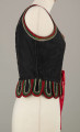 E/16876/ML - Gorset zszyty z 6 kawałków czarnej satyny, podszyty lnianą podszewką. Z przodu rozcięcie usztywnione fiszbinami oraz haftkami do przewlekania wstążeczki. Od pasa dookoła opadają klapki „taszki”. Przód wzdłuż rozcięcie wycięcie wokół szyi, brzegi pach i taszki ozdobione czerwoną, zieloną i białą wełnianą krepinką. Plecy zdobione ornamentem wykonanym ściegiem krzyżykowym. Szyty ręcznie.