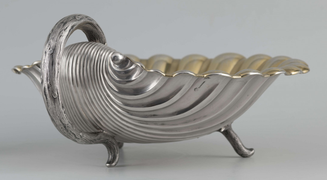 S/Mt/504/ML - Patera z uchwytem, w formie muszli przegrzebka ustawionej poziomo na  dwóch nóżkach - trzecią nóżkę tworzy zakończenie pionowo umocowanego esowatego ucha. 
Na odwrocie sygnatura segmentowa:
- znak miejski Petersburga
- znak imienny złotnika  