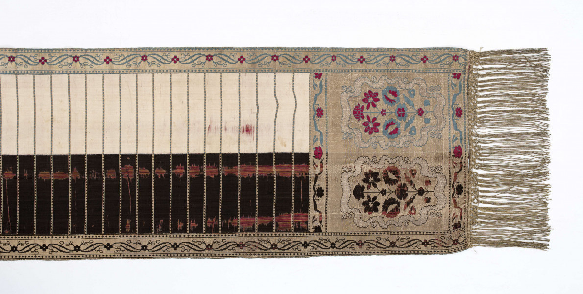 Pas kontuszowy 4-stronny
Ornament:
głowy - dwa krzaczki kwiatowe otoczone medalionami z wijącej się wstęgi
środek ( wciąż)- poprzeczne gładkie pólka
obwódki - z motywem kostki i rombów
obrzeżenia pionowe z motywem podwójnej przeplatającej się wici roślinnej, poziome - z motywem wijacej sie wstążki z kwiatami
Kolor:
pr. - tło głów i obrzeżeń srebrne, ornament brązowy z błękitem i amarantem, pólka w połowie brązowe (czarne ?), w połowie kremowe
l. - tło połowy głów i obrzeżeń błękitne oraz  w połowie pólek amarantowe, druga połowa głów i obrzeżeń brązowa oraz pólek - amarantowa
W narożnikach sygnatura wytkana 