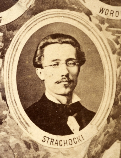 Fotografie w odcieniu sepii umieszczone na tle drzew i roślin, w centralnym miejscu postać kobiety ze sztandarem i aniołkami, wkomponowane widoki budowanej stacji, mostu kolejowego i lokomotywy. Największe zdjęcie w górnej, środkowej części bez podpisu, prawdopodobnie inż. głównej kolei nadwiślańskiej Tadeusz Chrzanowski lub jego następca Walery Titkow. Wśród podobizn pracownicy Biura Głównego Inżyniera: inż. Włodzimierz Stanisławski - pomocnik głównego inżyniera; inż. Feliks Kucharzewski -  pomocnik naczelnika biura; Feliks Kamocki - naczelnik kancelarii; Witold Lanci - naczelnik Wydz. Architektury; dr Wacław Lasocki- służba zdrowia; Władysław Radwan - sprawy zakupu gruntów; inż. Stanisław hr Scipio - projektant mostów kolejowych i jego współpracownicy: inż. Stefan Zieliński, inż. Maurycy Machalski, inż. Feliks Kucharzewski. Fotografia w passe - partout, za szkłem, oprawiona w drewnianą, profilowaną ramę.