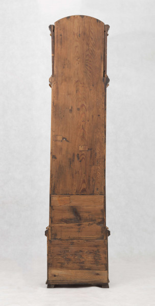 Tarcza w kształcie kwadratu zwieńczonego półkolem, złocona, w narożach ornamenty odlewane z brązu, złocone; pierścień  godzinowy srebrzony z rzymskimi oznaczeniami godzin i zaznaczonymi minutami, wewnątrz tarcza sekundnika, tarczka budzika, plakietka z sygnaturą 