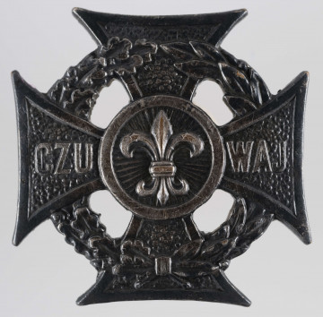 ML/MART/500 - Krzyż harcerski 4-ramienny wykonany z metalu, na środku lilijka harcerska, krzyż otaczają liście wawrzynu; napis na bocznych ramionach 