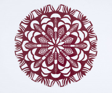 Wycinanka kolista z glansowanego wiśniowego papieru. Ornament geometryczno-roślinny. Środek wycinanki wypełnia ośmiopłatkowy stylizowany kwiat o śred. 13,5 cm o ażurowych płatkach. Motyw otoczony ażurowym ornamentem złożonym z falistych linii i stylizowanych płatków. Zewnętrzny okrąg wycinanki składa się ze stylizowanych wielopłatkowych kwiatków i ażurowych elementów prostokątnych.  
