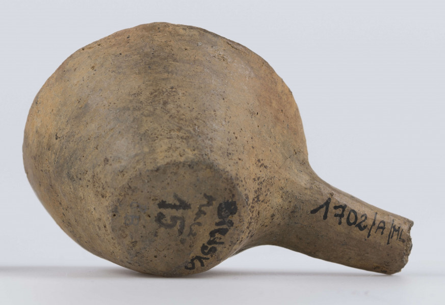 1702/A/ML - dno płaskie, ścianki proste, wylew zawinięty do wewnątrz; krawędź zaokrąglona; pod krawędzią umieszczono trzymadełko prostopadłe do ścianki, o przekroju owalnym, ułamane