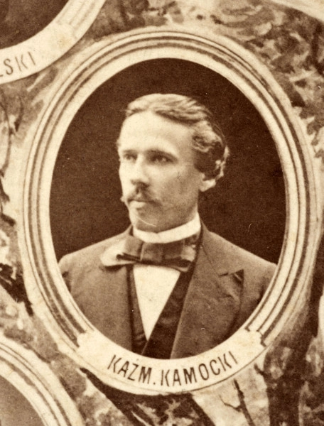 Fotografie w odcieniu sepii umieszczone na tle drzew i roślin, w centralnym miejscu postać kobiety ze sztandarem i aniołkami, wkomponowane widoki budowanej stacji, mostu kolejowego i lokomotywy. Największe zdjęcie w górnej, środkowej części bez podpisu, prawdopodobnie inż. głównej kolei nadwiślańskiej Tadeusz Chrzanowski lub jego następca Walery Titkow. Wśród podobizn pracownicy Biura Głównego Inżyniera: inż. Włodzimierz Stanisławski - pomocnik głównego inżyniera; inż. Feliks Kucharzewski -  pomocnik naczelnika biura; Feliks Kamocki - naczelnik kancelarii; Witold Lanci - naczelnik Wydz. Architektury; dr Wacław Lasocki- służba zdrowia; Władysław Radwan - sprawy zakupu gruntów; inż. Stanisław hr Scipio - projektant mostów kolejowych i jego współpracownicy: inż. Stefan Zieliński, inż. Maurycy Machalski, inż. Feliks Kucharzewski. Fotografia w passe - partout, za szkłem, oprawiona w drewnianą, profilowaną ramę.