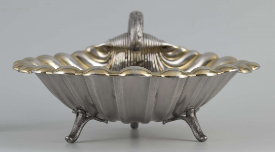 S/Mt/504/ML - Patera z uchwytem, w formie muszli przegrzebka ustawionej poziomo na  dwóch nóżkach - trzecią nóżkę tworzy zakończenie pionowo umocowanego esowatego ucha. 
Na odwrocie sygnatura segmentowa:
- znak miejski Petersburga
- znak imienny złotnika  