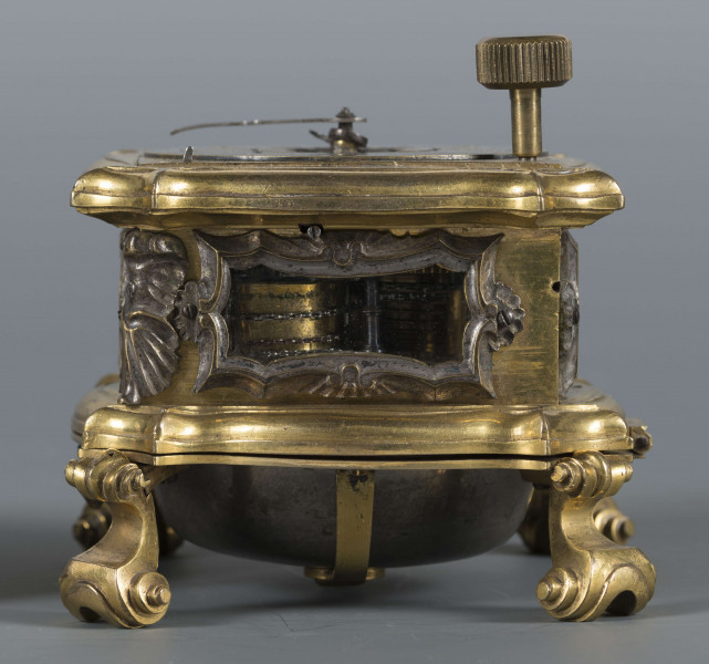 S/Mt/428/ML - Mechanizm o szkielecie płytowym, kwadratowym, łączonym balaskami. Wychwyt szpindlowy regulowany balansem włosowym; napęd sprężynowy chodu ze slimakiem wyrównawczym z funkcją bicia godzin i minut. Umieszczony w szkatule kwadratowej o falistych brzegach, na 4 nóżkach wolutowych; ścianki boczne oszklone w ozdobnie profilowanych ramkach, w narożach ornamenty muszlowo-wolutowe. W tarczy otwory naciągów przysłaniane, w narożniku wyłącznik biciawyłącznik bicia. Pierścień godzinowy srebrzony z rzymskimi oznaczeniemi godzin, arabskimi minut oraz kreskowa skala minutowa. Dwie proste wskazówki: godzinowa i minutowa. Na płycie dolnej mechanizmu obok koka, kółko regulacji chodu zegara: Avance Retard. Dwa młotki w formie muszli, dwie czasze zdwonków koncentrycznie umieszczone w klapie podstawy. 
Pośrodku tarczy dwie plakietki z dzieloną sygnaturą: 