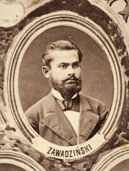 Fotografie w odcieniu sepii umieszczone na tle drzew i roślin, w centralnym miejscu postać kobiety ze sztandarem i aniołkami, wkomponowane widoki budowanej stacji, mostu kolejowego i lokomotywy. Największe zdjęcie w górnej, środkowej części bez podpisu, prawdopodobnie inż. głównej kolei nadwiślańskiej Tadeusz Chrzanowski lub jego następca Walery Titkow. Wśród podobizn pracownicy Biura Głównego Inżyniera: inż. Włodzimierz Stanisławski - pomocnik głównego inżyniera; inż. Feliks Kucharzewski -  pomocnik naczelnika biura; Feliks Kamocki - naczelnik kancelarii; Witold Lanci - naczelnik Wydz. Architektury; dr Wacław Lasocki- służba zdrowia; Władysław Radwan - sprawy zakupu gruntów; inż. Stanisław hr Scipio - projektant mostów kolejowych i jego współpracownicy: inż. Stefan Zieliński, inż. Maurycy Machalski, inż. Feliks Kucharzewski. Fotografia w passe - partout, za szkłem, oprawiona w drewnianą, profilowaną ramę.