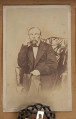 Tableau szklone zewnętrznie, w ramie, zawiera na tekturowym podłożu 15 fotografii uczestników powstania z terenu Wołynia. Pośrodku brak jednej, większej fotografii. Zdjęcia wykonane w sepii, w formacie pocztówkowym, niektóre z nich są podpisane pod spodem i na odwrociu: Eugeniusz Rdułtowski, Herkulan Kardussowski, F. Boryczewski, Antoni Straszewicz, Alfons Romanowski, Adam Hreczyna, Jan Grabis, Antoni Szymkiewicz.
Niektóre fotografie mają na kartonikach wyciskane napisy w języku rosyjskim. W środku tableau, pod pierwszym rzędem zdjęć przymocowany krzyżyk wykonany z chleba i tabaki, dekorowany motywem różyczek. Nad krzyżykiem druciana korona cierniowa, na niej krzyżyk z metalu z gałązką palmową. Niżej, pod brakującą fotografią lufka (?) z tektury, pierścionek i mały medalion ze Świętą Rodziną. Poniżej przymocowany grzebień rogowy, jakucki z napisem w języku rosyjskim i datą: 1864. Całość w ozdobnej ramie z dekoracyjnymi narożnikami, koroną, herbami Polski, Litwy, herbem z literą S. 