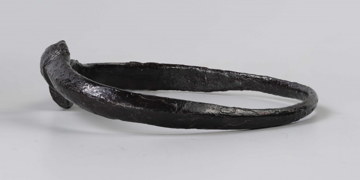 824/A/ML/1 - Żelazna bransoleta ze stylizowanymi wężowymi główkami. W części środkowej przekrój trapezowaty, przy główkach trójkątny.