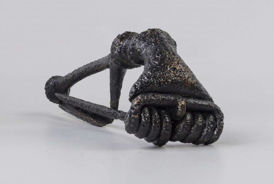 Fibula z brązu o ośmiozwojowej sprężynie i górnej cięciwie. Główka rozszerzająca się ku sprężynie, z dwoma grzebykami na kabłąku i trzecim na końcu nóżki. Typ Almgren 65 ?