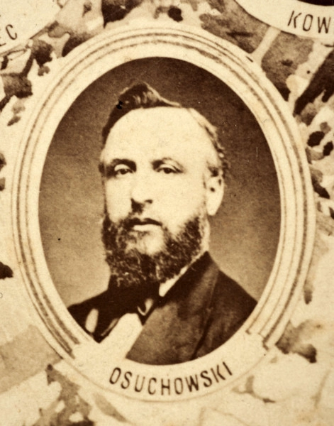 Fotografie w odcieniu sepii umieszczone na tle drzew i roślin, w centralnym miejscu postać kobiety ze sztandarem i aniołkami, wkomponowane widoki budowanej stacji, mostu kolejowego i lokomotywy. Największe zdjęcie w górnej, środkowej części bez podpisu, prawdopodobnie inż. głównej kolei nadwiślańskiej Tadeusz Chrzanowski lub jego następca Walery Titkow. Wśród podobizn pracownicy Biura Głównego Inżyniera: inż. Włodzimierz Stanisławski - pomocnik głównego inżyniera; inż. Feliks Kucharzewski -  pomocnik naczelnika biura; Feliks Kamocki - naczelnik kancelarii; Witold Lanci - naczelnik Wydz. Architektury; dr Wacław Lasocki- służba zdrowia; Władysław Radwan - sprawy zakupu gruntów; inż. Stanisław hr Scipio - projektant mostów kolejowych i jego współpracownicy: inż. Stefan Zieliński, inż. Maurycy Machalski, inż. Feliks Kucharzewski. Fotografia w passe - partout, za szkłem, oprawiona w drewnianą, profilowaną ramę.