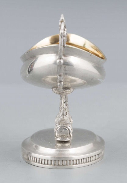 S/Mt/511/ML - Solniczka w formie łódki wspartej na dwóch delfinach, z owalną podstawą, z dwoma uchami z wici roślinnej. Brzeg czarki wywinięty, podstawa lekko podniesiona a jej brzeg zdobiony pionowym karbowaniem. Na spodzie sygnatura:
- imienna 