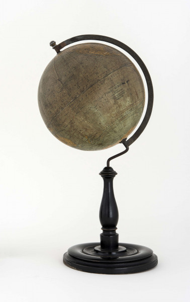 Globus bez tytułu, roku wydania i granic państwowych. Brak hipsometrii, powierzchnia kontynentów jest bladożółta za wyjątkiem białej Antarktydy. Na lądach naniesiono rzeki, pustynie i jeziora zaznaczono szrafurą. Największe góry oznaczono metodą kreskową (za pomocą 