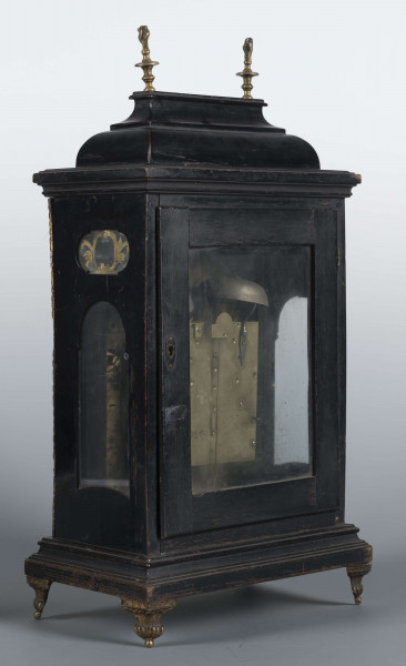 S/Mt/531/ML - Obudowa szafkowa, czworoboczna ze schodkowym zwieńczeniem, pokryta czarną politurą, oszklona z czterech stron, na czterech nóżkach z mosiądzu; w górnych narożnikach mosiężne sterczyny w formie płonących wazonów. Mechanizm chodu i bicia o napędzie sprężynowym, z wahadłem i dwoma dzwonkami; bicie godzin i kwadransów, budzik i repetier. Tarcza biało emaliowana z czarnymi cyframi arabskimi godzin i minut, w niej trzy otwory na osie sprężyn; trzy wskazówki, godzinowa i minutowa - ozdobne, sekundowa prosta. W górnej części tarczy sygnatura pisana ozdobną kursywą: M.G. / Jurkiewicz /  w Lublinie. Powyżej tarczy wycięcie z widocznym wahadełkiem kontrolnym i trzy mniejsze emaliowane tarcze: środkowa z miniaturą pejzażową, boczne z wyłączeniem chodu i bicia.