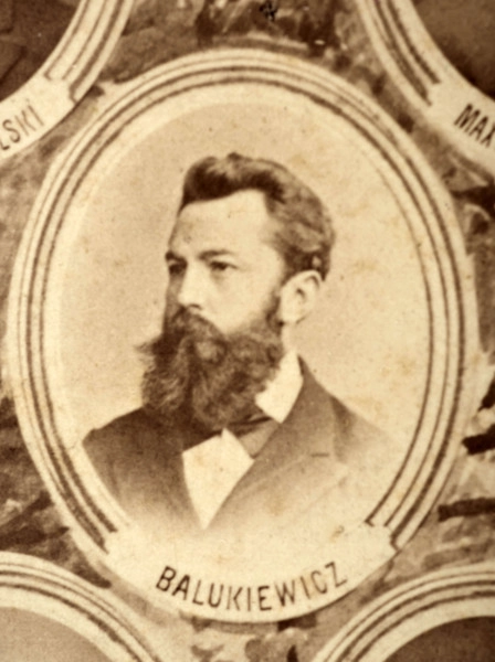 Fotografie w odcieniu sepii umieszczone na tle drzew i roślin, w centralnym miejscu postać kobiety ze sztandarem i aniołkami, wkomponowane widoki budowanej stacji, mostu kolejowego i lokomotywy. Największe zdjęcie w górnej, środkowej części bez podpisu, prawdopodobnie inż. głównej kolei nadwiślańskiej Tadeusz Chrzanowski lub jego następca Walery Titkow. Wśród podobizn pracownicy Biura Głównego Inżyniera: inż. Włodzimierz Stanisławski - pomocnik głównego inżyniera; inż. Feliks Kucharzewski -  pomocnik naczelnika biura; Feliks Kamocki - naczelnik kancelarii; Witold Lanci - naczelnik Wydz. Architektury; dr Wacław Lasocki- służba zdrowia; Władysław Radwan - sprawy zakupu gruntów; inż. Stanisław hr Scipio - projektant mostów kolejowych i jego współpracownicy: inż. Stefan Zieliński, inż. Maurycy Machalski, inż. Feliks Kucharzewski. Fotografia w passe - partout, za szkłem, oprawiona w drewnianą, profilowaną ramę.