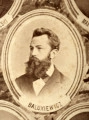 Fotografie w odcieniu sepii umieszczone na tle drzew i roślin, w centralnym miejscu postać kobiety ze sztandarem i aniołkami, wkomponowane widoki budowanej stacji, mostu kolejowego i lokomotywy. Największe zdjęcie w górnej, środkowej części bez podpisu, prawdopodobnie inż. głównej kolei nadwiślańskiej Tadeusz Chrzanowski lub jego następca Walery Titkow. Wśród podobizn pracownicy Biura Głównego Inżyniera: inż. Włodzimierz Stanisławski - pomocnik głównego inżyniera; inż. Feliks Kucharzewski -  pomocnik naczelnika biura; Feliks Kamocki - naczelnik kancelarii; Witold Lanci - naczelnik Wydz. Architektury; dr Wacław Lasocki- służba zdrowia; Władysław Radwan - sprawy zakupu gruntów; inż. Stanisław hr Scipio - projektant mostów kolejowych i jego współpracownicy: inż. Stefan Zieliński, inż. Maurycy Machalski, inż. Feliks Kucharzewski. Fotografia w passe - partout, za szkłem, oprawiona w drewnianą, profilowaną ramę.