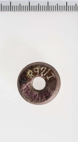 wykonany z łupka owruckiego; dwustożkowy, ostro profilowany; linia tworząca kształt dwustożkowy biegnie nieregularnie na różnych wysokościach; płasko ścięty przy otworze; otwór średniej wielkości, cylindryczny