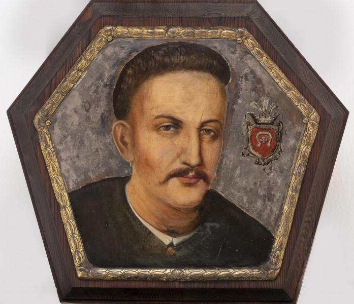 Portret trumienny męski z przedstawieniem nieznanego szlachcica herbu Lubicz. Pole obrazowe w kształcie nieforemnego sześciokąta. Ujęcie portretowanego od strony prawej, w zwrocie 3/4 do widza. Na neutralnym, srebrzonym tle - realistyczne przedstawienie szlachcica. Twarz potraktowana portretowo, ramiona płaszczyznowo zarysowane. Przedstawiony mężczyzna w średnim wieku, w typie sarmackim - długie wąsy, podgolone włosy, ubrany w czarny żupan spięty pod szyją czerwono-ugrowym guzem; widoczny fragment kołnierza białej koszuli. Twarz malowana laserunkowo, z próbą oddania cech charakterologicznych, pociągła. Długi, prosty nos, małe, lekko przymknięte oczy. Po prawej stronie herb szlachecki. W czerwonym polu tarczy herbowej - godło - srebrna podkowa zwrócona ocelami do dołu, pośrodku niej - srebrny krzyż kawalerski. Nad tarczą korona szlachecka z klejnotami w postaci trzech strusich piór oraz labry w formie stylizowanych liści akantu. Herb otoczony inicjałami 