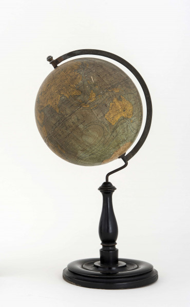 Globus bez tytułu, roku wydania i granic państwowych. Brak hipsometrii, powierzchnia kontynentów jest bladożółta za wyjątkiem białej Antarktydy. Na lądach naniesiono rzeki, pustynie i jeziora zaznaczono szrafurą. Największe góry oznaczono metodą kreskową (za pomocą 