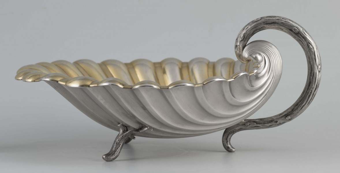 S/Mt/504/ML - Patera z uchwytem, w formie muszli przegrzebka ustawionej poziomo na  dwóch nóżkach - trzecią nóżkę tworzy zakończenie pionowo umocowanego esowatego ucha. 
Na odwrocie sygnatura segmentowa:
- znak miejski Petersburga
- znak imienny złotnika  