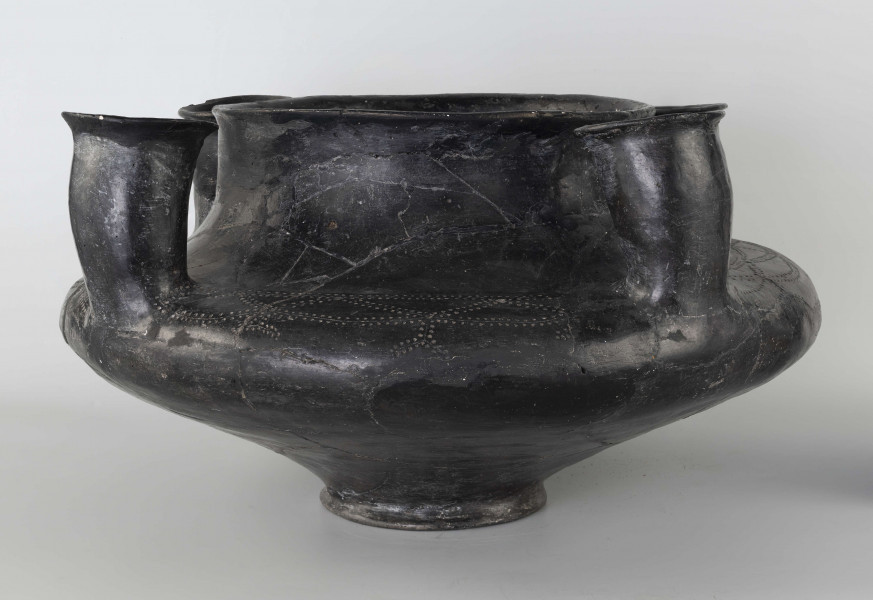 598/A/ML - naczynie kultowe (kernos) kultury pomorskiej; 
wymiary dodatkowe: 25,0 cm - średnica centralnego wylewu
opis: naczynie wazowate o czarnej, błyszczącej powierzchni, którego brzusiec został ozdobiony ornamentem złożonym z linii rytych oraz nakłuć; wokół głównego otworu posiada cztery symetrycznie rozmieszczone kielichy-rytony, które mają nieco wydęte ścianki boczne i kielichowato rozchylone na zewnątrz krawędzie otworów; rytony łączą się z głównym otworem kanalikami; 