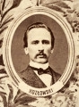 Fotografie w odcieniu sepii umieszczone na tle drzew i roślin, w centralnym miejscu postać kobiety ze sztandarem i aniołkami, wkomponowane widoki budowanej stacji, mostu kolejowego i lokomotywy. Największe zdjęcie w górnej, środkowej części bez podpisu, prawdopodobnie inż. głównej kolei nadwiślańskiej Tadeusz Chrzanowski lub jego następca Walery Titkow. Wśród podobizn pracownicy Biura Głównego Inżyniera: inż. Włodzimierz Stanisławski - pomocnik głównego inżyniera; inż. Feliks Kucharzewski -  pomocnik naczelnika biura; Feliks Kamocki - naczelnik kancelarii; Witold Lanci - naczelnik Wydz. Architektury; dr Wacław Lasocki- służba zdrowia; Władysław Radwan - sprawy zakupu gruntów; inż. Stanisław hr Scipio - projektant mostów kolejowych i jego współpracownicy: inż. Stefan Zieliński, inż. Maurycy Machalski, inż. Feliks Kucharzewski. Fotografia w passe - partout, za szkłem, oprawiona w drewnianą, profilowaną ramę.