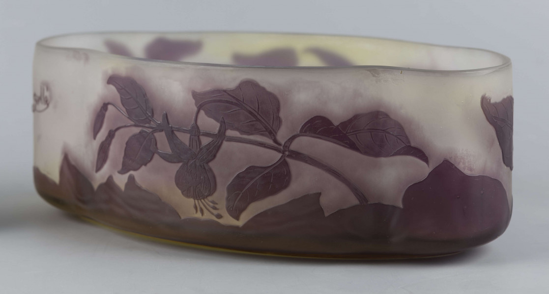 S/CS/1385/ML - Żardiniera ze szkła grubościennego, bezbarwnego, matowanego, podbarwianego żółtym i liliowym pudrem; na niskiej spiczasto-owalnej podstawie korpus o ściankach pionowo sfalowanych, u dołu lekko zaokrąglony, górna krawędź ścięta. Korpus pokryty warstwą liliową, w niej trawiony wzór roslinny: gałązka fuksji z kwiatami, przy dnie dookoła  pasmo liliowe o nieregularnym wykroju.
 