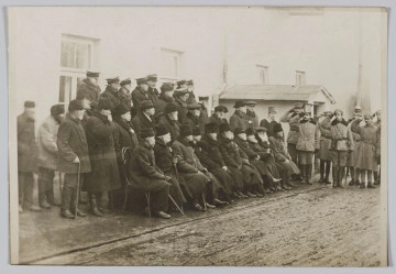 ML/H/310 - Na fotografii grupa weteranów powstania styczniowego, licząca 34 osoby. Ustawieni są w trzech rządach: pierwszy rząd siedzi na krzesłach, drugi stoi, trzeci rząd stoi na podwyższeniu. Część mężczyzn ubrana w czamaraki. Z prawej strony salutujące wojsko. Fotografia wykonana na tle budynków. Na odwrociu wykropkowane linie jak na pocztówkach oraz odręczny napis: Powstańcy z 1863 r.