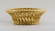 Koszyczek owalny głęboki; dno pełne od zewnątrz obwiedzione warkoczem, boki z okrągłych wałków przeplecionych ukośnie, połączonych profilowaną obręczą tworzącą krawędź. W lustrze (na dnie) dekoracja reliefowa: pośrodku bukiet kwiatów w wazonie, wokół brzegu wić laurowa z owocami. Całość pokryta połyskliwą glazurą w kolorze jasnego ugru.
 