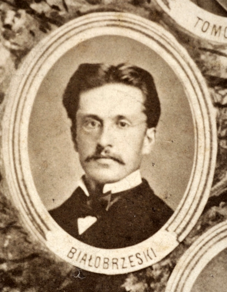 Fotografie w odcieniu sepii umieszczone na tle drzew i roślin, w centralnym miejscu postać kobiety ze sztandarem i aniołkami, wkomponowane widoki budowanej stacji, mostu kolejowego i lokomotywy. Największe zdjęcie w górnej, środkowej części bez podpisu, prawdopodobnie inż. głównej kolei nadwiślańskiej Tadeusz Chrzanowski lub jego następca Walery Titkow. Wśród podobizn pracownicy Biura Głównego Inżyniera: inż. Włodzimierz Stanisławski - pomocnik głównego inżyniera; inż. Feliks Kucharzewski -  pomocnik naczelnika biura; Feliks Kamocki - naczelnik kancelarii; Witold Lanci - naczelnik Wydz. Architektury; dr Wacław Lasocki- służba zdrowia; Władysław Radwan - sprawy zakupu gruntów; inż. Stanisław hr Scipio - projektant mostów kolejowych i jego współpracownicy: inż. Stefan Zieliński, inż. Maurycy Machalski, inż. Feliks Kucharzewski. Fotografia w passe - partout, za szkłem, oprawiona w drewnianą, profilowaną ramę.