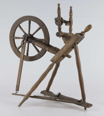 E/16647/ML - Kołowrotek poziomy, drewniany, ozdobnie toczony. Drewno niemalowane. Podstawa to 3 skośnie ustawione nóżki. Dwie z nich osadzone w wąskiej listwie. Górne końce nóżek osadzone w prostokątnej pochyłej grubej desce (11 x 32 x 4 cm). Stanowi ona podstawę do osadzenia koła napędowego i szpuli zwijającej nici. W niej zamocowany uchwyt połączony ze śrubą, która reguluje położenie szpuli. Koło osadzone na metalowej ośce posiada 8 toczonych ozdobnie szprych. Jeden koniec ośki połączony pionową ruchomą listewką z pedałem wprawiającym w ruch kołowrotek. Szpula osadzona również na metalowej ośce.