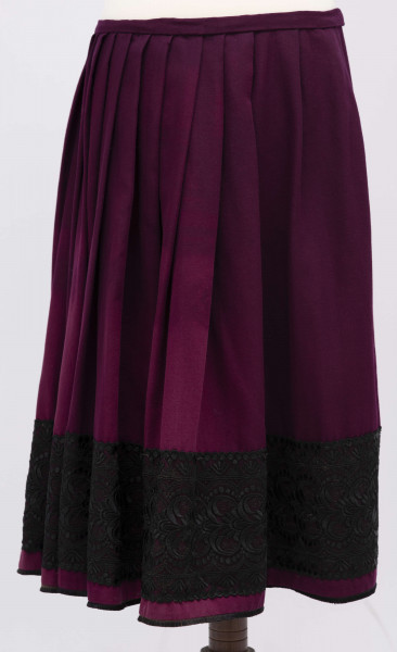 E/11633/ML - Spódnica z wełenki ciemnofioletowej, wszyta w pasek. Zszyta z 4 brytów. Wykończona czarną szczoteczką, powyżej pas (szer. 17 cm) tiulowej czarnej koronki o stylizowanym ornamencie roślinnym.